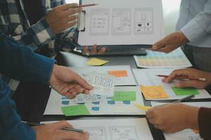 Close up ux developer and ui designer brainstorming about mobile app interface wireframe design on table with customer breif and color code at modern office.Creative digital development agency photo