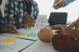 Close up ux developer and ui designer brainstorming about mobile app interface wireframe design on table with customer breif and color code at modern office.Creative digital development agency photo