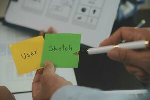 Close up ux developer and ui designer brainstorming about mobile app interface wireframe design on table with customer breif and color code at modern office.Creative digital development agency photo