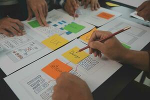 Close up ux developer and ui designer brainstorming about mobile app interface wireframe design on table with customer breif and color code at modern office.Creative digital development agency photo