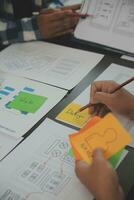 Close up ux developer and ui designer brainstorming about mobile app interface wireframe design on table with customer breif and color code at modern office.Creative digital development agency photo