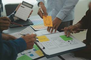Close up ux developer and ui designer brainstorming about mobile app interface wireframe design on table with customer breif and color code at modern office.Creative digital development agency photo