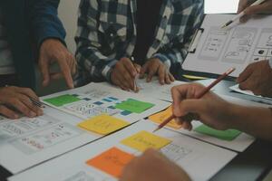 Close up ux developer and ui designer brainstorming about mobile app interface wireframe design on table with customer breif and color code at modern office.Creative digital development agency photo