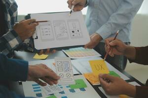 Close up ux developer and ui designer brainstorming about mobile app interface wireframe design on table with customer breif and color code at modern office.Creative digital development agency photo