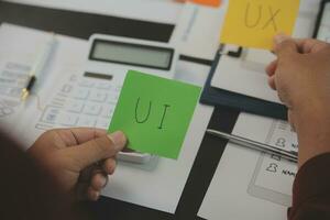 Close up ux developer and ui designer brainstorming about mobile app interface wireframe design on table with customer breif and color code at modern office.Creative digital development agency photo