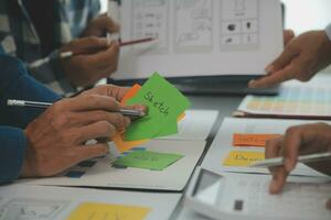 Close up ux developer and ui designer brainstorming about mobile app interface wireframe design on table with customer breif and color code at modern office.Creative digital development agency photo