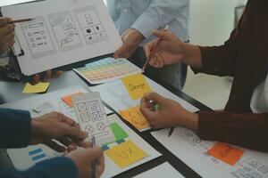 Close up ux developer and ui designer brainstorming about mobile app interface wireframe design on table with customer breif and color code at modern office.Creative digital development agency photo