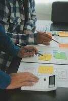 Close up ux developer and ui designer brainstorming about mobile app interface wireframe design on table with customer breif and color code at modern office.Creative digital development agency photo