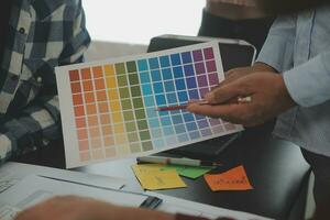 Close up ux developer and ui designer brainstorming about mobile app interface wireframe design on table with customer breif and color code at modern office.Creative digital development agency photo