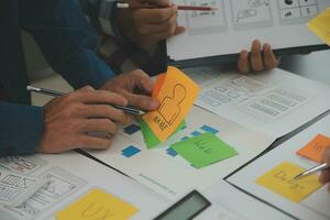 Close up ux developer and ui designer brainstorming about mobile app interface wireframe design on table with customer breif and color code at modern office.Creative digital development agency photo