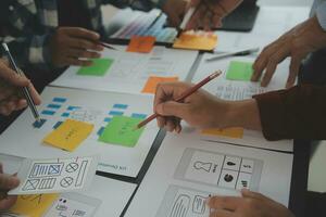 Close up ux developer and ui designer brainstorming about mobile app interface wireframe design on table with customer breif and color code at modern office.Creative digital development agency photo
