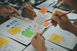 Close up ux developer and ui designer brainstorming about mobile app interface wireframe design on table with customer breif and color code at modern office.Creative digital development agency photo