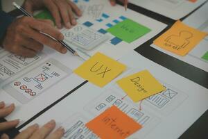 Close up ux developer and ui designer brainstorming about mobile app interface wireframe design on table with customer breif and color code at modern office.Creative digital development agency photo