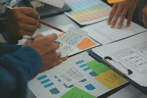 Close up ux developer and ui designer brainstorming about mobile app interface wireframe design on table with customer breif and color code at modern office.Creative digital development agency photo