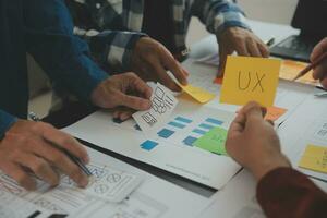 Close up ux developer and ui designer brainstorming about mobile app interface wireframe design on table with customer breif and color code at modern office.Creative digital development agency photo