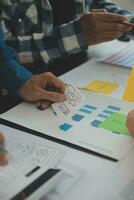 Close up ux developer and ui designer brainstorming about mobile app interface wireframe design on table with customer breif and color code at modern office.Creative digital development agency photo