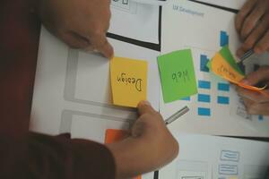 Close up ux developer and ui designer brainstorming about mobile app interface wireframe design on table with customer breif and color code at modern office.Creative digital development agency photo