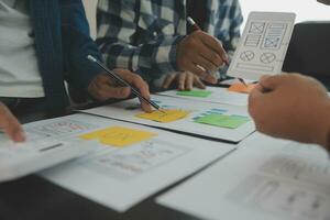 Close up ux developer and ui designer brainstorming about mobile app interface wireframe design on table with customer breif and color code at modern office.Creative digital development agency photo