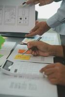 Close up ux developer and ui designer brainstorming about mobile app interface wireframe design on table with customer breif and color code at modern office.Creative digital development agency photo