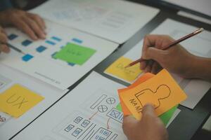 Close up ux developer and ui designer brainstorming about mobile app interface wireframe design on table with customer breif and color code at modern office.Creative digital development agency photo