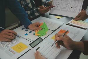 Close up ux developer and ui designer brainstorming about mobile app interface wireframe design on table with customer breif and color code at modern office.Creative digital development agency photo