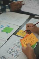 Close up ux developer and ui designer brainstorming about mobile app interface wireframe design on table with customer breif and color code at modern office.Creative digital development agency photo
