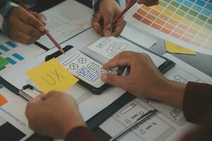 Close up ux developer and ui designer brainstorming about mobile app interface wireframe design on table with customer breif and color code at modern office.Creative digital development agency photo