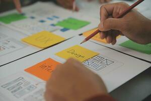Close up ux developer and ui designer brainstorming about mobile app interface wireframe design on table with customer breif and color code at modern office.Creative digital development agency photo