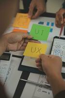 Close up ux developer and ui designer brainstorming about mobile app interface wireframe design on table with customer breif and color code at modern office.Creative digital development agency photo