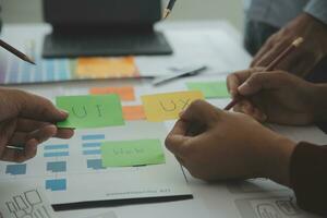 Close up ux developer and ui designer brainstorming about mobile app interface wireframe design on table with customer breif and color code at modern office.Creative digital development agency photo