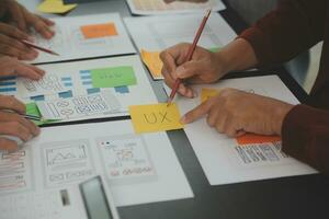 Close up ux developer and ui designer brainstorming about mobile app interface wireframe design on table with customer breif and color code at modern office.Creative digital development agency photo