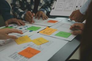 Close up ux developer and ui designer brainstorming about mobile app interface wireframe design on table with customer breif and color code at modern office.Creative digital development agency photo