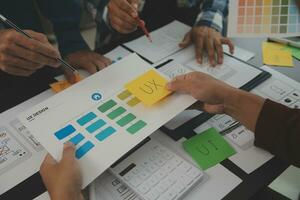 Close up ux developer and ui designer brainstorming about mobile app interface wireframe design on table with customer breif and color code at modern office.Creative digital development agency photo