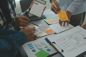 Close up ux developer and ui designer brainstorming about mobile app interface wireframe design on table with customer breif and color code at modern office.Creative digital development agency photo
