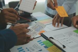 Close up ux developer and ui designer brainstorming about mobile app interface wireframe design on table with customer breif and color code at modern office.Creative digital development agency photo