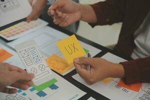 Close up ux developer and ui designer brainstorming about mobile app interface wireframe design on table with customer breif and color code at modern office.Creative digital development agency photo