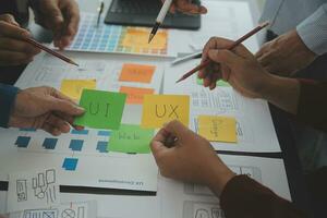 Close up ux developer and ui designer brainstorming about mobile app interface wireframe design on table with customer breif and color code at modern office.Creative digital development agency photo