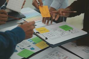 Close up ux developer and ui designer brainstorming about mobile app interface wireframe design on table with customer breif and color code at modern office.Creative digital development agency photo