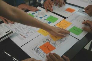 Close up ux developer and ui designer brainstorming about mobile app interface wireframe design on table with customer breif and color code at modern office.Creative digital development agency photo