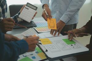 Close up ux developer and ui designer brainstorming about mobile app interface wireframe design on table with customer breif and color code at modern office.Creative digital development agency photo