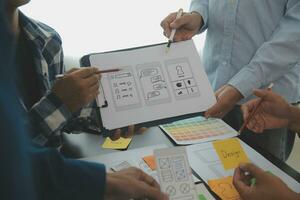 Close up ux developer and ui designer brainstorming about mobile app interface wireframe design on table with customer breif and color code at modern office.Creative digital development agency photo