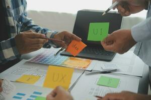 Close up ux developer and ui designer brainstorming about mobile app interface wireframe design on table with customer breif and color code at modern office.Creative digital development agency photo