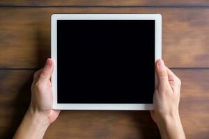 Top view hand holding tablet on wooden table photo