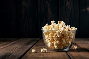Popcorn in the glass bowl on old wooden background photo