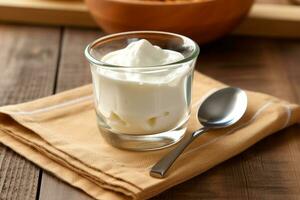 Yogurt in glass with spoon on wooden background photo