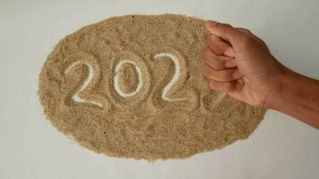 A hand removes the number 3 replacing it with the number 4 on the sand, change of year 2023 to 2024. Concept of change of new year 2023 to 2024 video