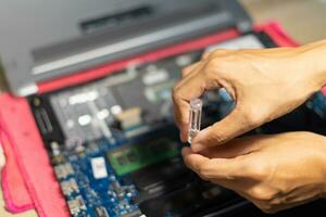 the hand is using a screwdriver to tighten the nut. To change the battery of a notebook computer by yourself. Changing electronic devices by yourself concept. photo