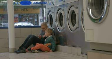 Mother and child using mobile in the laundry video