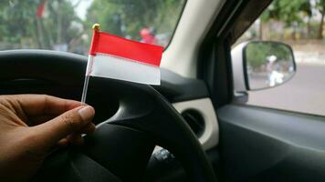 Hand holding Indonesian flag in the car to welcome Indonesia's independence day photo