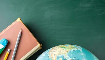 globe, pencil, pen and book on a green blackboard background and empty space on left side photo